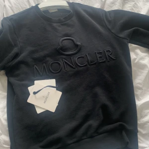 Moncler Maglia Sweatshirt - Moncler maglia sweatshirt. NFC-taggen har åkt av, men det går att skriva in serienummret på code.moncler.com vilket visar att den är äkta. Använt skick, men inga fläckar eller hål. Endast tagsen som visas på bilden medföljer. INGET KVITTO