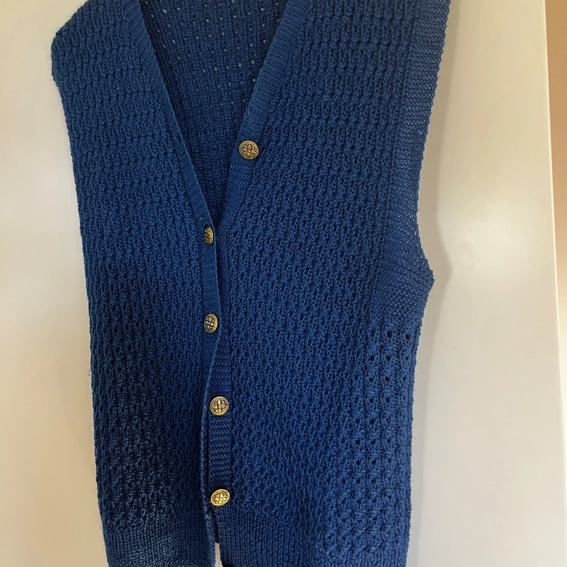 Blå stickad väst med guldknappar