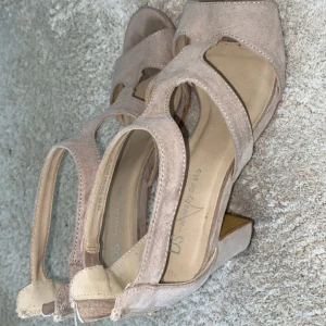 Beige sandaler med klack från DS - Säljer ett par snygga beige sandaler med klack från DS. De har en öppen tå och stilrena remmar som ger en elegant look. Perfekta för sommarens alla fester eller en dag på stan. Använda men i bra skick!