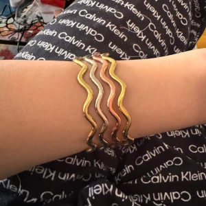 Vågformade armband i guld, silver och koppar - Säljer ett set med vågformade armband i tre olika färger: guld, silver och koppar. Armbanden är stilrena och unika, perfekta för att ge din outfit en extra touch. De är i nyskick och passar till både vardag och fest. Köp dem nu och ge din smyckessamling en uppgradering!