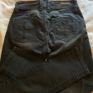 Slim fit y2k jeans med feta fickor  - Svarta Slim fit jeans från märket Blue Monkey Svarta slim fit jeans med kors på fickorna🤑 Byxorna är miss me/rock revival liknande🤯 Finns inga defekter på byxorna  Storlek: W27 & L32 (XS)
