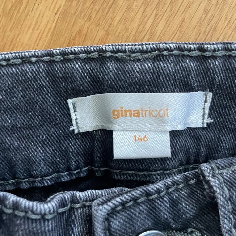 Säljer ett par snygga mörkgrå jeans från Gina Tricot. De har en klassisk femficksdesign med knappar och dragkedja fram. Jeansen har bootcut och är perfekta för både vardag och fest. De är i bra skick och redo för en ny ägare!. Jeans & Byxor.