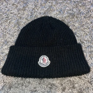 Moncler mössa - En svart moncler mössa. Använd bara några fåtal gånger. Den är i jätte bra skick och har alla tags.