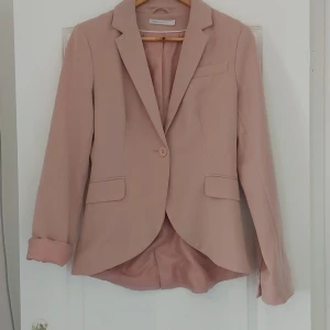 Beige kavaj från Zara - Säljer en snygg  kavaj i färgen puderrosa. Kavajen har en klassisk design med en enkel knapp framtill och två fickor. Ärmarna är långa och har två dekorativa knappar vid ärmsluten. Perfekt för     "Back to work" eller till vardag som en tunnare "jacka", så snygg! 🩷