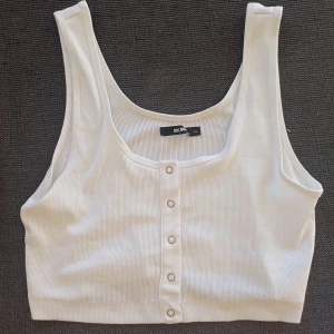 Vit ribbad linnetopp från Bik Bok - Säljer en superfin vit ribbad linnetopp från Bik Bok. Toppen har en enkel och stilren design med knappar framtill. Den är i nyskick utan defekter!☺️☺️🤍