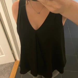 Svart ärmlös topp från Gina Tricot - Säljer en snygg svart ärmlös topp med volang!