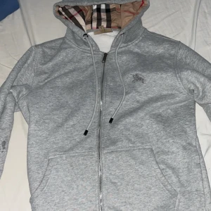 Grå Burberry zip hoodie - Använd fåtal gånger skick 9/10 inga fel på den Storlek M men funkar bra som S säljer för 799 för snabb affär