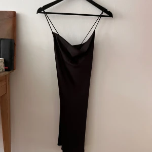 Svart långklänning från Monki - Säljer en elegant svart kortklänning från Monki. Klänningen har tunna axelband och en smickrande passform som passar perfekt för festliga tillfällen. Materialet i silke är väldigt bekvämt, vilket gör den bekväm att bära hela kvällen. Perfekt för nyår eller andra speciella tillfällen! 