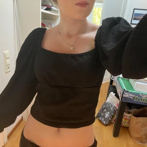 Svart croppad topp med puffärmar - Säljer en snygg svart croppad topp med puffärmar. Toppen har en fyrkantig halsringning och är tillverkad i ett bekvämt material. Perfekt för både vardag och fest! 🖤