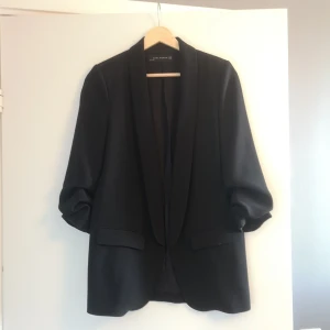 Svart kavaj från Zara Woman - Elegant svart kavaj från Zara Woman i storlek XS med "uppsydda" armar för en casual feel. Köptes på Sellpy men den har tyvärr inte kommit till användning. På botten är den nopprig. ***Köpare står för frakt om inget annat anges!