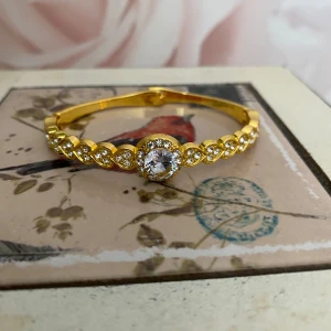 Nytt guldfärgat armband  - Guldfärgat armband med vackra kristaller. Okänt material och märke och är nytt.