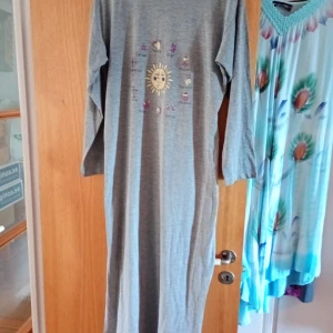 Grå långklänning med astrologiskt tryck - Säljer en superfin grå nattlinne med ett coolt astrologiskt tryck på framsidan. nattlinne har långa ärmar och är perfekt för en avslappnad dag eller en mysig kväll hemma. Den är i fint skick och väldigt bekväm att ha på sig. Passar perfekt året runt.