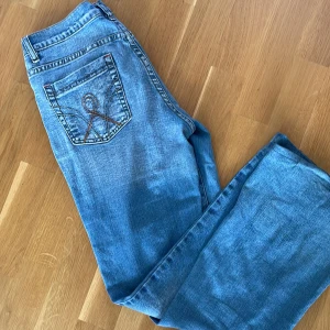 💓Vintage Jeans💓 - Säljer världens snyggaste lågmidjade jeans med jätte coolt tryck på bakfickorna!! Säljer då färgen inte passar på mig!💓Jättebra skick!! Midjemått rakt över 37! Innerbenslängd 73 🤗 Öppen för prisförändring.