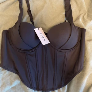Korsettopp - Oanvänd korsettopp från NAKD i storlek 75B.