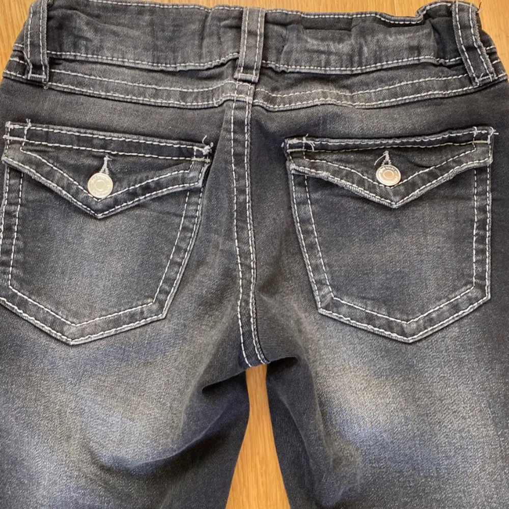 Säljer ett par snygga mörk gråa  bootcut jeans med coola detaljer. De har en dragkedja och knappar fram samt fickor med knappar bak. Inga defekter på dem 💗 . Jeans & Byxor.