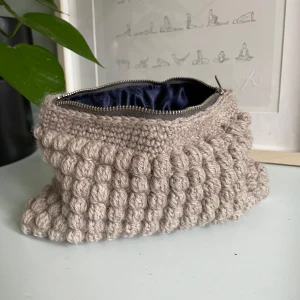 Virkad necessär  - Superfin virkad necessär med bubblig textur. Perfekt julklapp till mamma, kompis, syskon, passar till alla! Insidan är fodrad med ett mörkblått satin liknande tyg som ger en känsla av lyx. Perfekt för smink, småsaker eller som en söt detalj i badrummet! Egengjord 🧶