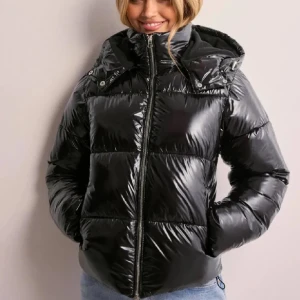 Svart glansig pufferjacka med huva - Säljer en snygg svart pufferjacka från Nelly i storlek XS använd max 2 gånger så iprincip helt ny. Skicka prisförslag!💕💕