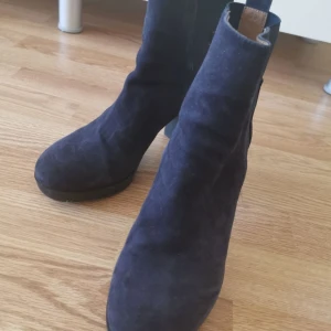 Mörkblå mocka boots från Rodebjer - Säljer ett par snygga mörkblå boots i mocka. De har en bekväm klack och elastiska paneler på sidorna för enkel på- och avtagning. Perfekta för höst och vinter, och de ger en stilren look till vilken outfit som helst.