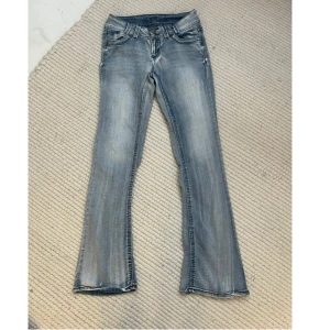 Grå jeans från Wallflower - Snygga trendiga grå bootcut jeans från Wallflower. De har en cool tvättad look och dubbla knappar i midjan. Bakfickorna har snygga detaljer. Midjemåttet: ca 76 Innerbenslängden: ca 79 