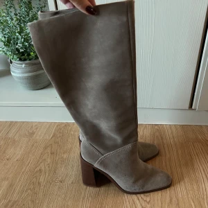 Mocka stövlar Mango - Beigea mockastövlar från mango med brun klacka. Använda 2 gånger. Lite märken på klacken annars bra skick.