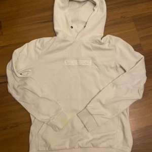 Vit hoodie från Peak Performance Storlek S - Säljer en stilren vit hoodie från Peak Performance i storlek S. Den är supermjuk och perfekt för både vardag och chill. Hoodien har en broderad logga på bröstet och en klassisk känguruficka. Perfekt för höst och vår!