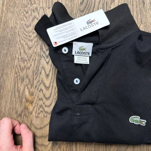 Lacoste piké  - Svart fin piké säljer pågrund av årstiden passar även de som har storleken L 
