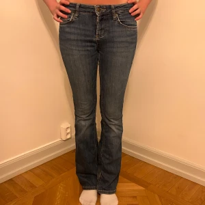 Blå bootcut jeans - Säljer ett par snygga blå bootcut jeans i bra skick. De har en klassisk femficksdesign och är perfekta för både vardag och fest. Jeansen är midwaist och har en bekväm passform som sitter snyggt över höfterna.