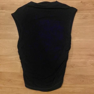 Svart topp från Gina Tricot - Säljer en stilren svart topp från Gina Tricot. Perfekt för både vardag och fest. Toppen är ärmlös och har en enkel design som gör den lätt att matcha med olika outfits. Materialet känns mjukt och bekvämt mot huden.