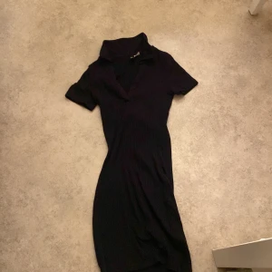 Svart klänning från H&M Divided - Snygg svart klänning från H&M Divided i storlek XS. Den har en ribbad struktur och korta ärmar, perfekt för både vardag och fest. Klänningen är i bra skick och har en stilren design som passar till många tillfällen.