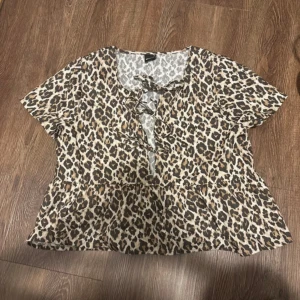 Leopardmönstrad blus från Gina Tricot - Säljer en snygg leopardmönstrad blus från Gina Tricot i storlek S. Blusen har korta ärmar och en volangdetalj framtill. Perfekt för en trendig look, oavsett om det är till vardags eller fest.