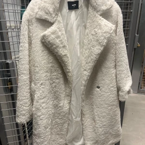 Vit teddyjacka från Bik Bok - Mysig vit teddyjacka från Bik Bok i storlek XS. Perfekt för kyliga dagar med sin fluffiga och varma design. Jackan har en klassisk krage och långa ärmar, vilket gör den både stilren och bekväm. Ett måste för höst- och vintergarderoben! 🧥❄️