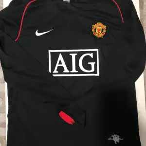 Säljer en snygg 🤩 svart långärmad Manchester United tröja från Nike med AIG som sponsor. Tröjan har klubbens emblem på bröstet och 'Ronaldo 7' på ryggen. Perfekt för fans av laget och spelaren! 🖤perfekt skick nästan helt ny.