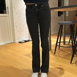 Svarta bootcut jeans - Säljer ett par svarta bootcut jeans i bra skick. De är medelmidjade och har en klassisk femficksdesign med knapp och dragkedja fram. Grunt Texas low flare. Perfekta för både vardag och fest! 🖤har ett lagat hål på höger knä, se bild.