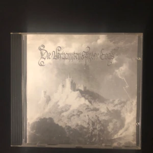 Die Verbannten Kinder Evas CD - Säljer en rare CD med titeln 'Die Verbannten Kinder Evas'. Omslaget har en mystisk, svartvit bild av ett slott på en bergstopp. Baksidan listar låtar som 'Einleitung' och 'Darkened Skies'. Skivan är från General Inquisitor Torquemado's Releases. Perfekt för dig som gillar gotisk och atmosfärisk musik. 
