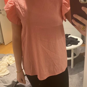 Rosa blus från Shein - Säljer en söt rosa blus från Shein i storlek S. Blusen har korta puffärmar och en lös passform, perfekt för vår och sommar. Materialet är lätt och bekvämt, vilket gör den idealisk för både vardag och festliga tillfällen.