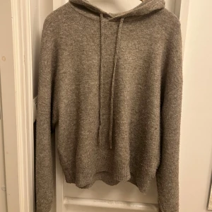 Beige stickad hoodie - Mysig beige stickad hoodie i loose fit. Perfekt för kyliga höst- och vinterdagar. Den har en bekväm huva med dragsko och långa ärmar. Passar både till hemmamys och en avslappnad dag ute. 