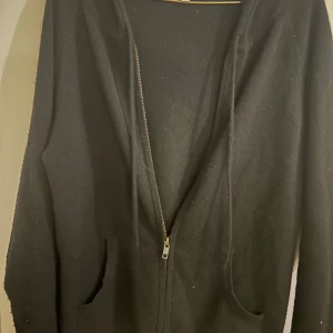 Kashmire hoodie från Davida - Säljer en stilren svart kashmire hoodie från Davida i storlek M. Den har en dragkedja framtill och praktiska fickor. Perfekt för både höst och vinter, och den är supermjuk och bekväm. Passar till alla tillfällen! 🖤