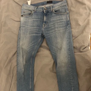Blå jeans från Tiger of Sweden - Säljer ett par snygga blå jeans från Tiger of Sweden. De har en klassisk femficksdesign och en bekväm passform. 