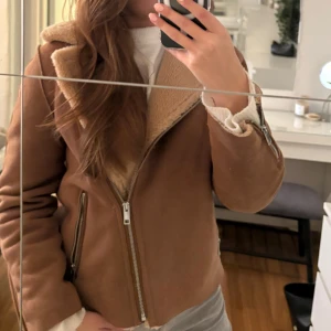 Brun mockajacka med foder - Säljer en snygg brun mockajacka med mysigt foder. Jackan har en dragkedja framtill och långa ärmar. Perfekt för höst och vinter, håller dig varm och stilren. Passar till både vardag och fest!🍂🧡