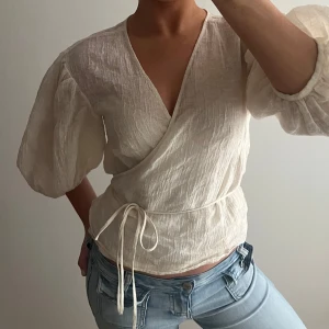 Vit omlottopp - Säljer en superfin vit omlottopp med knytband i midjan