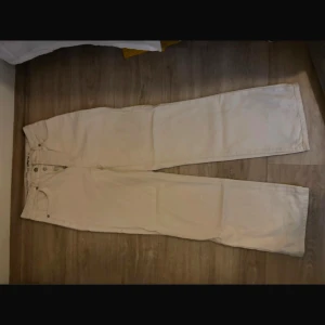 Vita jeansbyxor - Säljer ett par vita jeansbyxor i bra skick. De har en klassisk femficksdesign och knappar i midjan. Perfekta för en stilren look och passar till alla säsonger. Sköna och enkla att matcha med olika outfits!