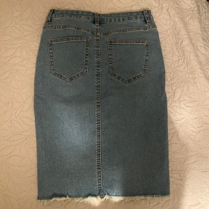 Jeanskjol med rå kant - Säljer en snygg jeanskjol i klassisk blå denim. Kjolen har en rå kant nertill för en trendig look och femficksdesign. Perfekt för både vardag och fest! 🥳