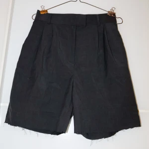 Svarta shorts från H&M - Snygga svarta shorts från H&M i storlek 40. De har en klassisk design med hög midja och veck framtill. Perfekta för både vardag och festliga tillfällen. Materialet är bekvämt och lätt, vilket gör dem idealiska för varmare väder.