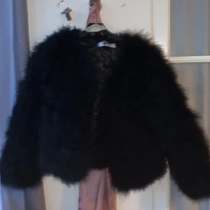 Svart fjäderjacka från Dennis Maglic - Säljer en supercool svart fjäderjacka från Dennis Maglic. Den är perfekt för att ge din outfit en extra edge. Jackan är fluffig och har en quiltad insida för extra komfort. Passar perfekt till både vardag och fest!