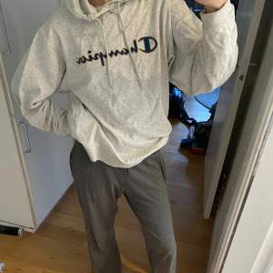 Säljer en superbekväm grå hoodie från Champion. Den har en klassisk passform med en stor logga på bröstet. Perfekt för chill dagar eller när du vill ha en avslappnad stil. Den är i bra skick och redo för nya äventyr!