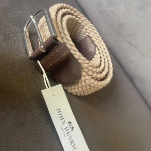 Beige flätat bälte från John Henric - Säljer ett helt oanvänt snyggt beige flätat bälte från John Henric. Storlek 43/110. Nypris 500kr mitt 199kr! Vid minsta fundering eller osäkerhet hör av dig! Fri frakt till 25/8