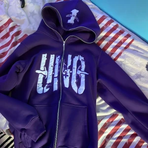 Lila hoodie med tryck - Säljer en lila hoodie med stort tryck på framsidan. Dragkedjan går ända upp till huvan. Köpt från USA.