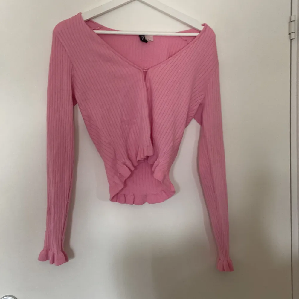 Säljer en superfin rosa ribbad tröja från H&M Divided. Den har en v-ringad design och långa ärmar med volangdetaljer vid ärmsluten. Perfekt för både vardag och fest! 💖. Tröjor & Koftor.