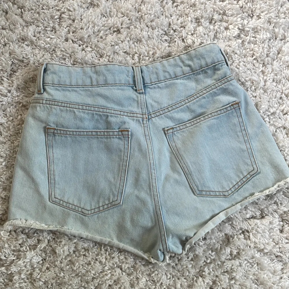 Säljer ett par ljusblå jeansshorts från H&M i storlek 36. De har en snygg fransig kant och klassisk femficksdesign. Perfekta för sommaren!. Shorts.