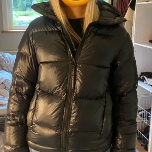 Peak performance jacka - Super snygg peak jacka i en glansig svart färg, nästan helt oanvänd och i väldigt fint skit förutom en lagningslapp som sitter inuti luvan, men som aldrig syns!💗💗skriv för fler frågor!!